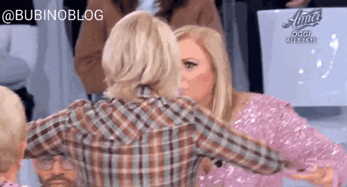 a woman in a plaid shirt is hugging another woman in a pink dress .