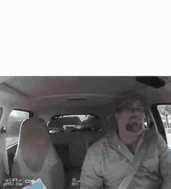 a man is driving a car with his mouth open .