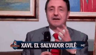 a man in a suit and tie is talking into a microphone with the words xavi el salvador cule written on the screen
