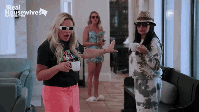 three women standing in front of a sign that says ' real housewives '