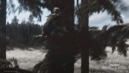 a poster for predator badlands shows a man standing in a tree