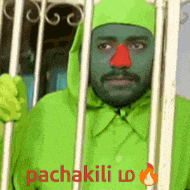 a man in a green costume with a red nose is behind bars with the words pachakili written on the bottom