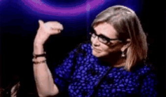 a woman wearing glasses and a blue shirt is dancing in a dark room .