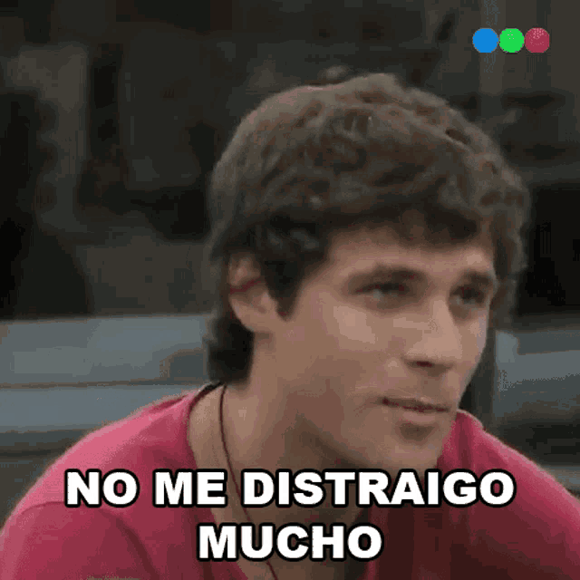 a man in a pink shirt is making a funny face and saying no me distraigo mucho .