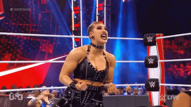 a woman is standing in a wrestling ring with her arms outstretched .