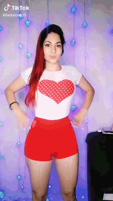 a woman wearing red shorts and a white shirt with a red heart on it
