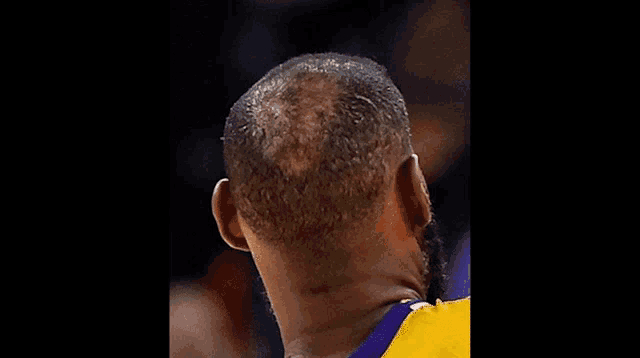 a man with a bald head wearing a yellow and purple jersey