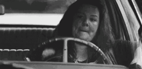 a woman is sitting in the driver 's seat of a car and crying .