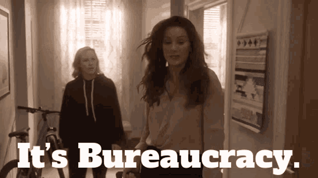 two women walking in a hallway with the words " it 's bureaucracy " on the bottom