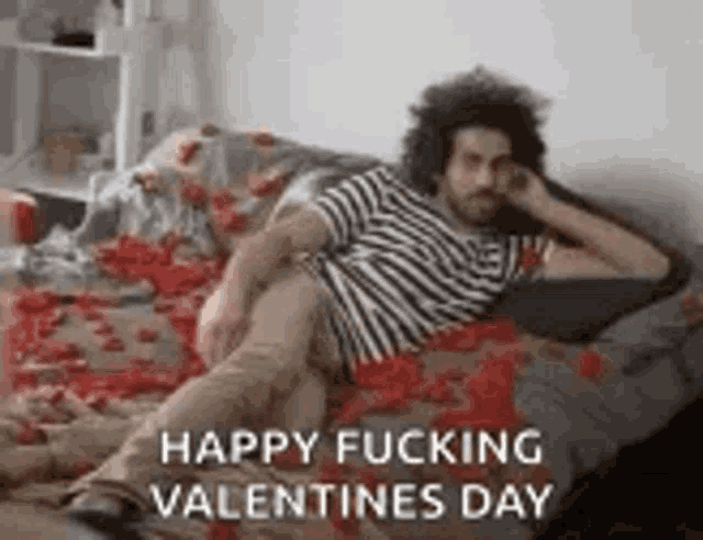 a man is laying on a couch covered in red roses .
