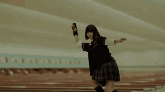 a girl in a school uniform is rollerblading in a bowling alley