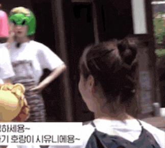a woman wearing a green alien mask is looking at another woman wearing a lion mask .