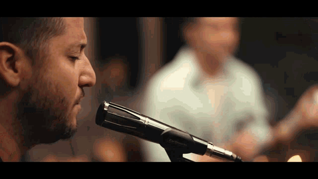 a close up of a man singing into a microphone that says sennheiser