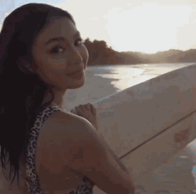 a woman in a leopard print bikini is holding a surfboard .
