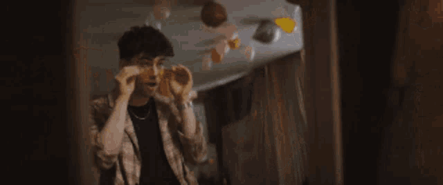 a man with curly hair is covering his face with his hands in a room .
