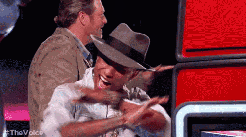 a man in a hat is hugging another man in a hat on a stage .