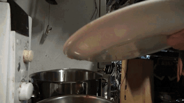 a person is holding a white plate in their hand in a kitchen