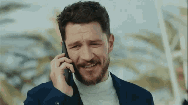 a man in a suit is talking on a cell phone and smiling .