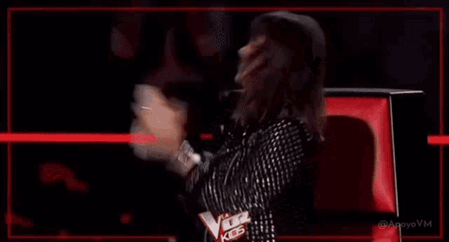 a woman in a leather jacket is standing on a stage with her arms in the air and smiling .