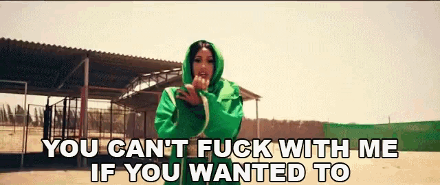 a woman in a green hoodie stands in front of a fence and says you can 't fuck with me if you wanted to
