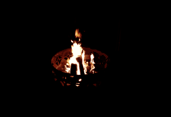 a fire is burning in a circular container in the dark