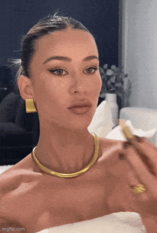 a woman wearing a gold necklace and gold earrings