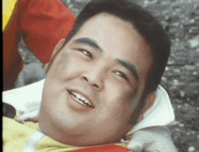 a man is smiling while laying on the ground with a bandage on his face .