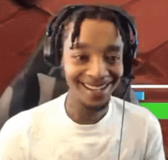 a young man wearing headphones is smiling and sitting in a chair .