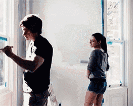 a man is painting a window while a woman stands behind him .