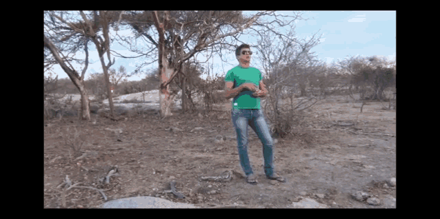 a man in a green shirt is standing in a desert