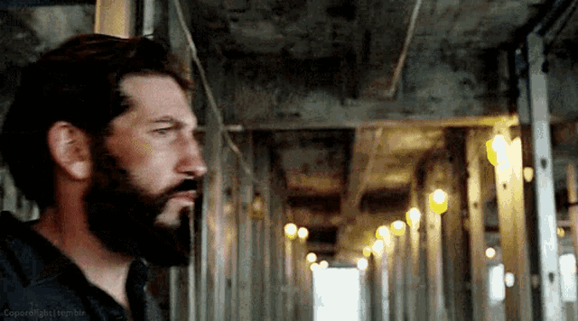 a man with a beard is standing in a hallway with a bunch of lights .