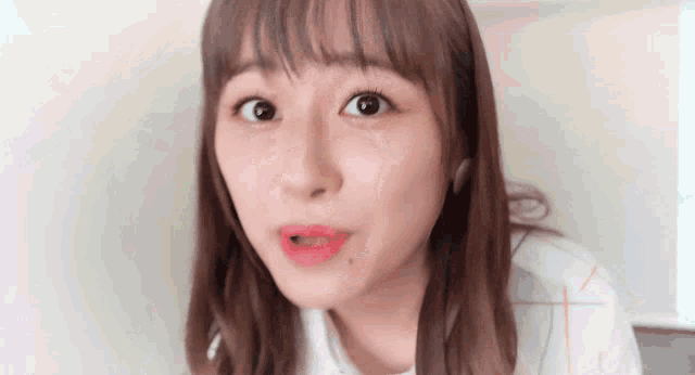 a close up of a woman 's face with a white shirt on