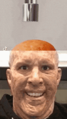 a close up of a man 's face with an orange on his head .