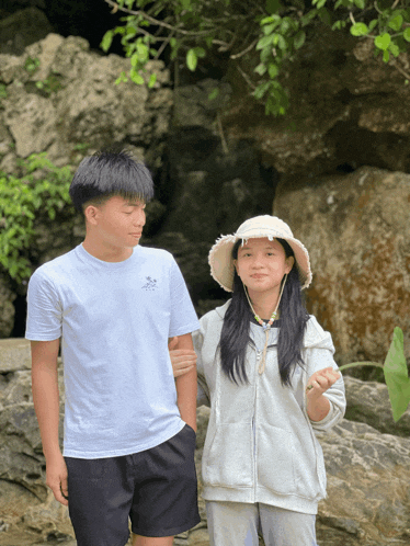 a boy and a girl standing next to each other with the girl wearing a white hat