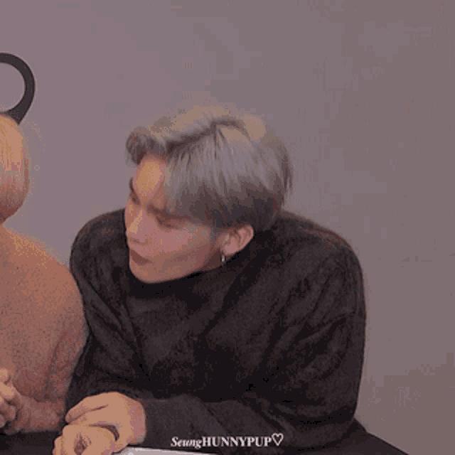 a man in a green sweater is talking to another man in a brown sweater