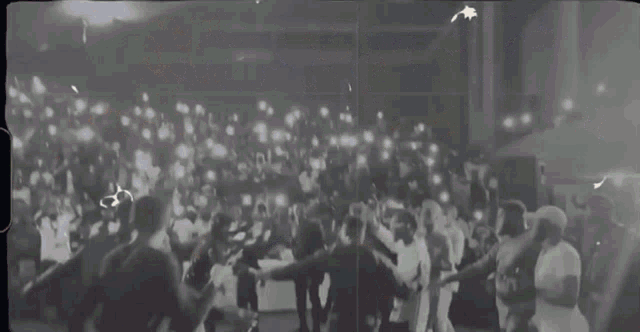 a crowd of people are gathered in a dark room with lights shining on them