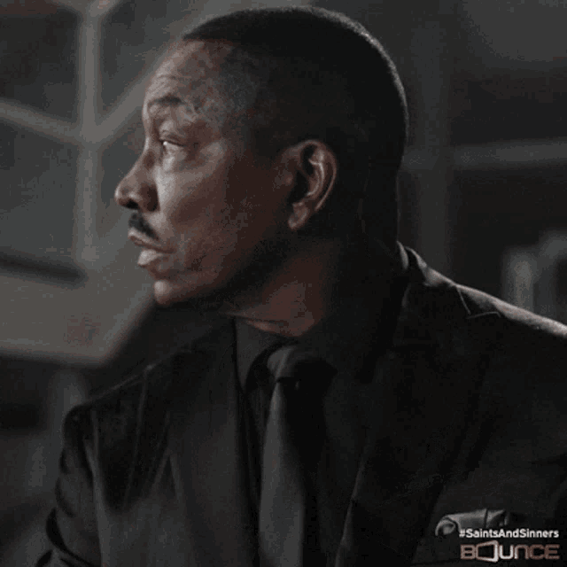 a man in a suit and tie is holding a gun with the words saints and sinners bounce on the bottom right