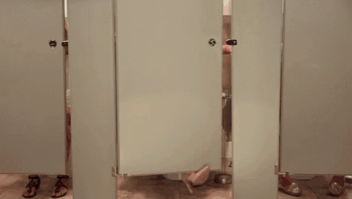 a woman in a blue dress is sitting on a toilet in a bathroom stall