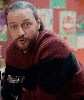 a man in a red and black striped sweater holds a glass of wine