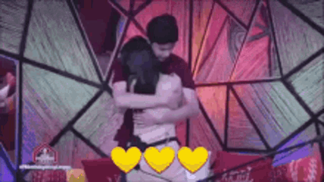 a man and a woman are hugging each other in front of a stained glass wall .