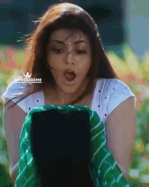 a woman with a surprised look on her face is holding a green and white striped blanket .