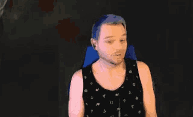 a man with blue hair and a beard is holding a black object .