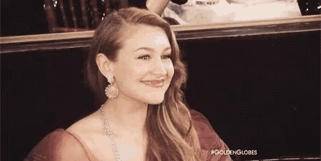 a woman in a red dress is smiling and wearing earrings .