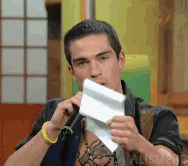 a man is holding a piece of paper in front of his mouth and the word alignment is visible in the corner