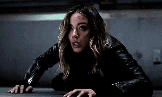 a woman in a black leather jacket is crawling on a floor .