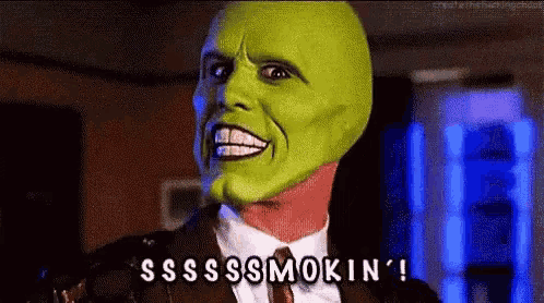 a man in a suit and tie with a green mask on his face is smoking .