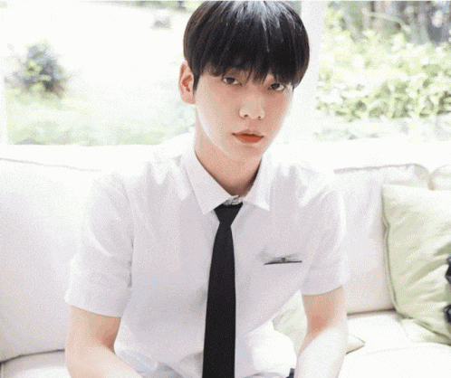 a young man is sitting on a couch wearing a white shirt and tie .