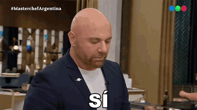 a bald man in a suit says " si " on a television show
