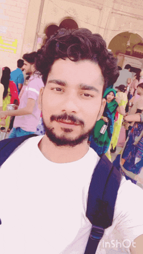 a man with a beard is taking a selfie in front of a group of people