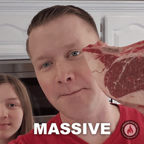 a man is holding a large piece of meat and the word massive is on the bottom
